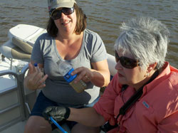 Stephanie Miles and Betty Bates work on their water sample while enjoying a dramatic sunset with an approaching storm on the Altamaha River Delta