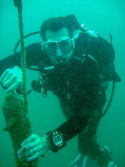 A scuba diver cleans off a black cylinder underwater.