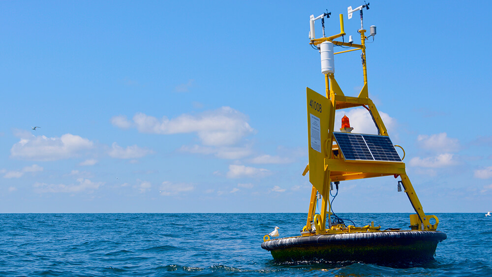 A yellow weather buoy floating on the surface of the ocean.
