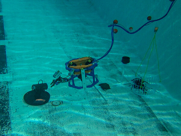 An underwater robot extends an arm to a PVC pipe to move it