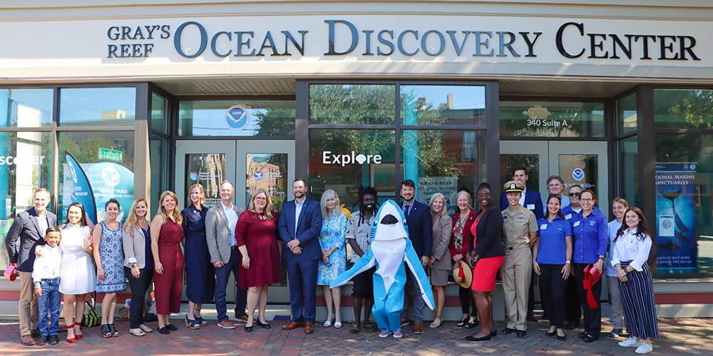 A group of people stand in front of the Gray's Reef Ocean Discovery Center as part of the building dedication ceremony.