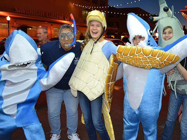 A group of people in ocean-themed costumes poses for a group picture inside of a movie theater